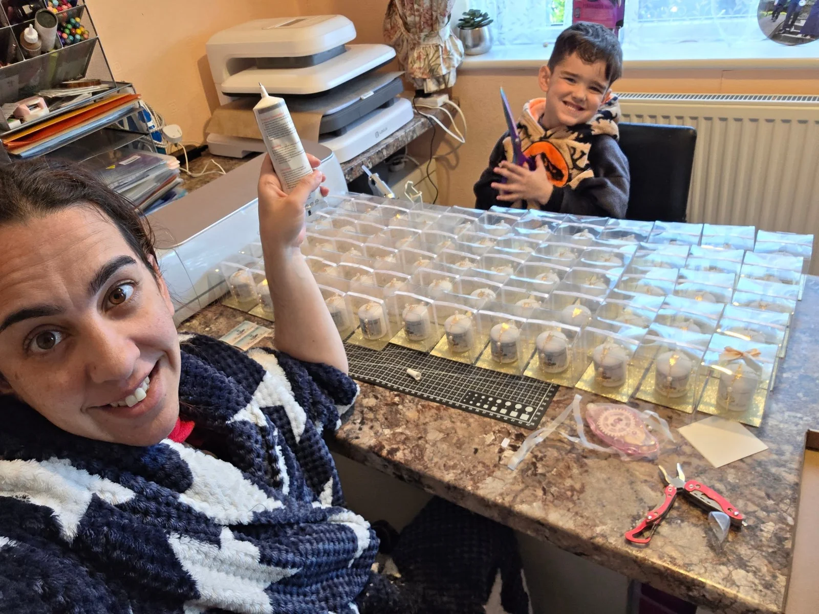 Lily working on handmade creations with a child in the background
